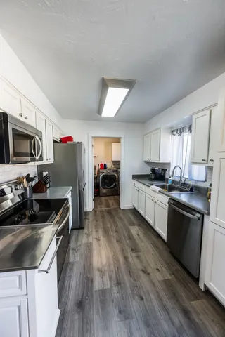 a kitchen with granite countertop a stove top oven a sink dishwasher and a refrigerator