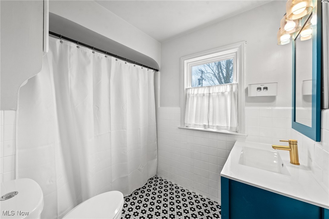 2323 Saybrook Road Cleveland, OH 44118 - Photo 17 of 42 Bathroom featuring a wainscoted wall, toilet, vanity, tile walls, and a shower with shower curtain
