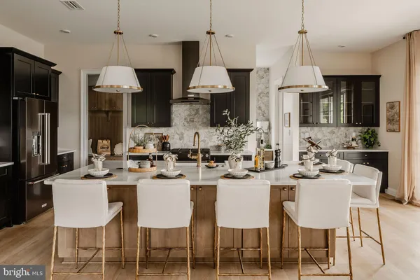 a dining room with stainless steel appliances a table chairs a sink and a refrigerator