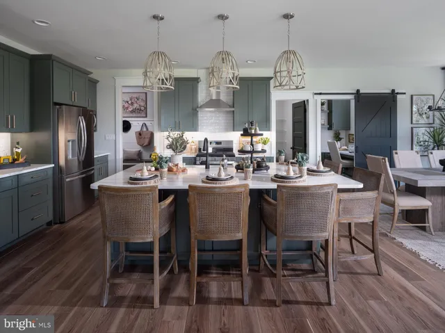 a dining room with stainless steel appliances kitchen island a table chairs and a kitchen view