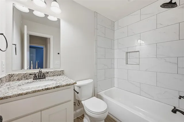 a bathroom with a granite countertop sink mirror toilet and bathtub
