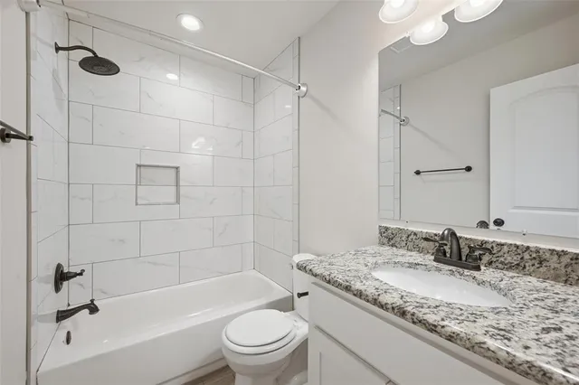 a bathroom with a granite countertop sink a toilet and bathtub