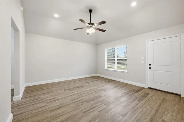 a view of an empty room with wooden floor and a window