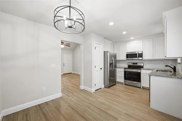 a kitchen with stainless steel appliances granite countertop a refrigerator a stove and a wooden floors