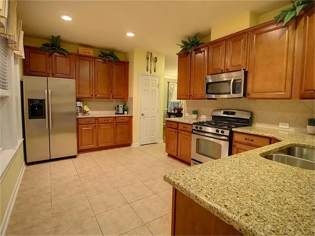 a kitchen with stainless steel appliances granite countertop a sink a stove and a refrigerator