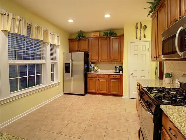 a kitchen with stainless steel appliances granite countertop a stove a sink and a refrigerator