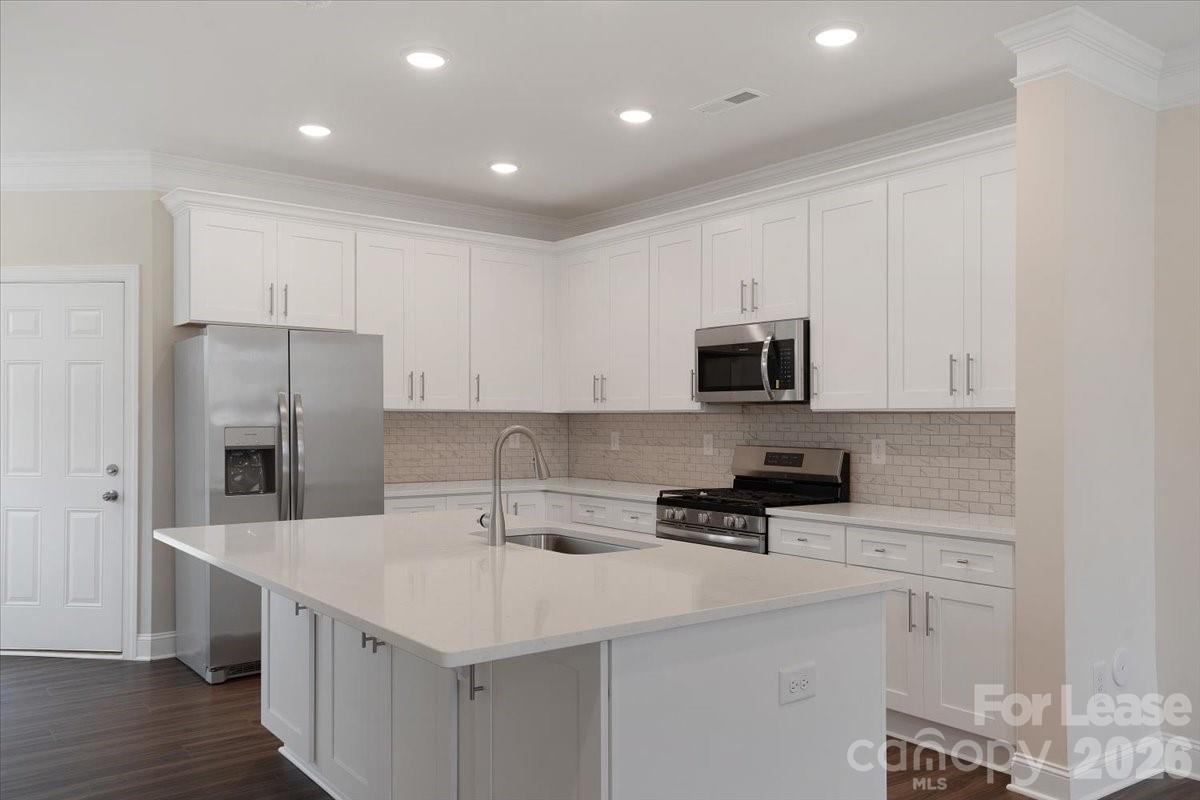 5569 Stafford Road Charlotte, NC 28215 - Photo 11 of 29 a kitchen with stainless steel appliances a sink a stove a microwave and cabinets