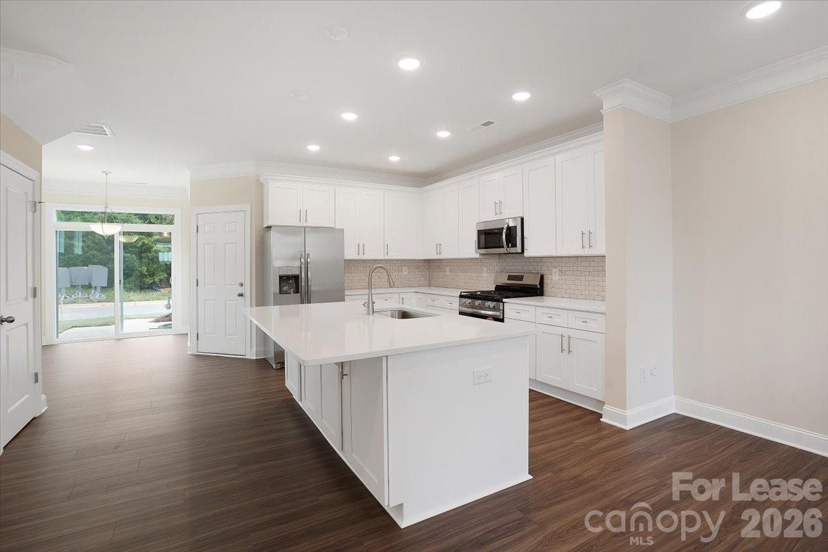 5569 Stafford Road Charlotte, NC 28215 - Photo 8 of 29 a kitchen with stainless steel appliances white cabinets a sink and wooden floor