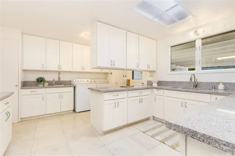a kitchen with granite countertop white cabinets sink and stainless steel appliances
