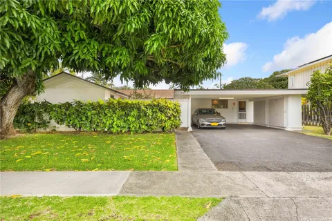 a car parked in front of a house next to a yard