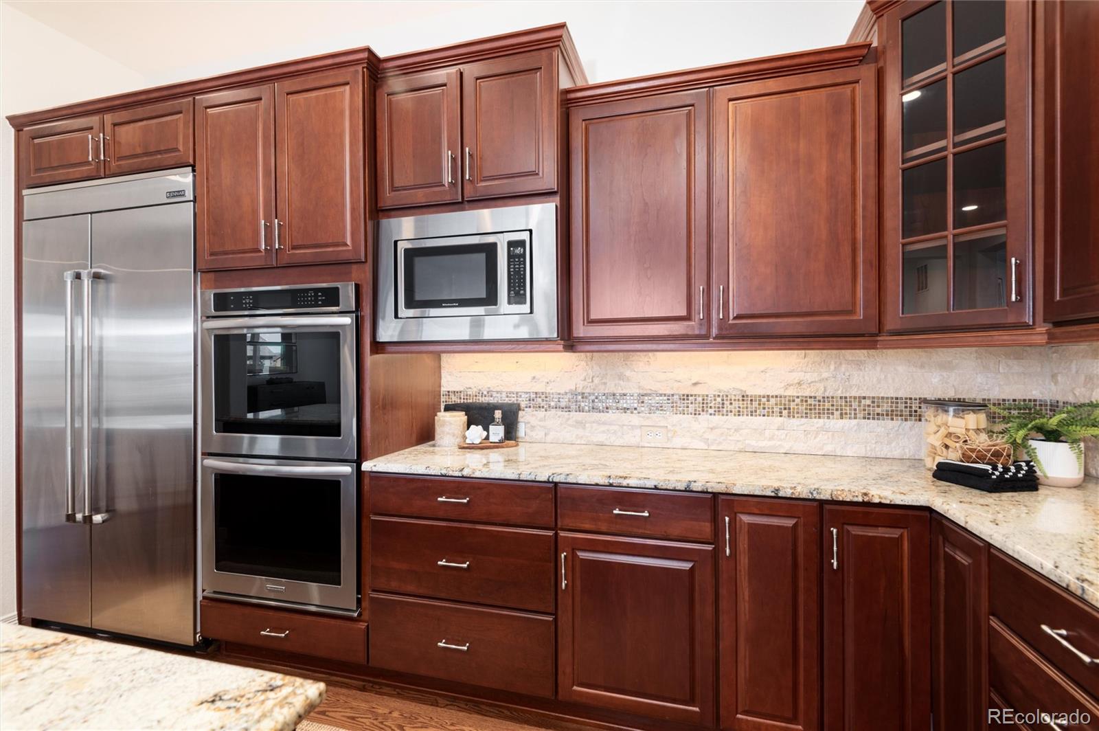 10698 Mountaingate Court Highlands Ranch, CO 80126 - Photo 12 of 47 a kitchen with granite countertop wooden cabinets and stainless steel appliances