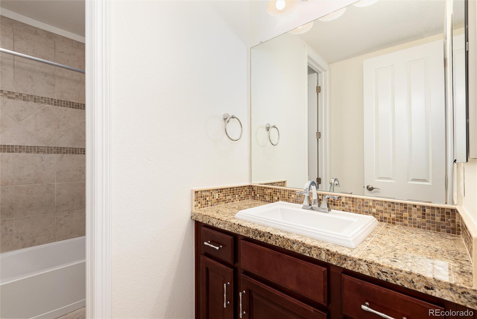 10698 Mountaingate Court Highlands Ranch, CO 80126 - Photo 33 of 47 a bathroom with a granite countertop sink and a mirror