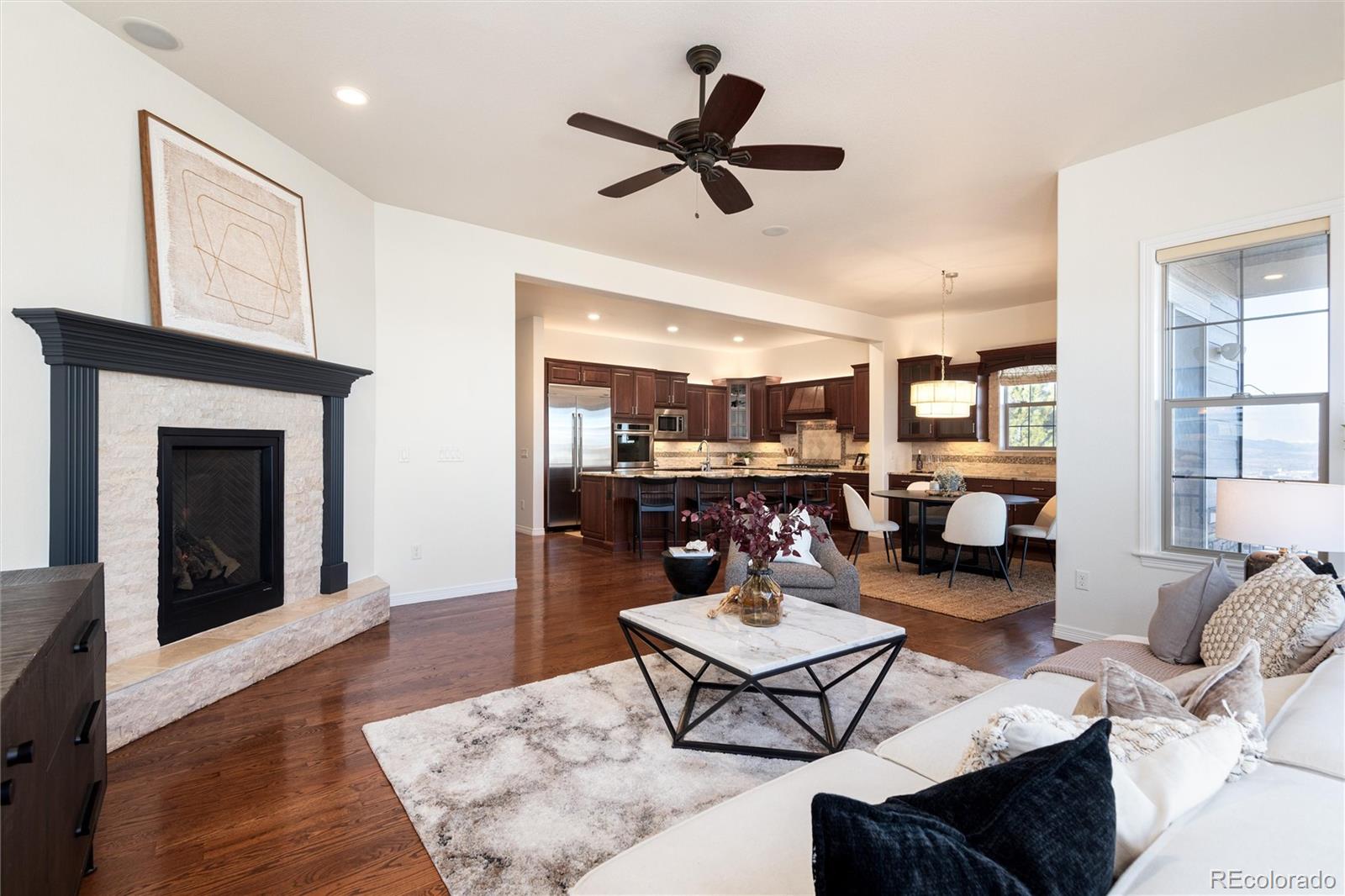 10698 Mountaingate Court Highlands Ranch, CO 80126 - Photo 6 of 47 a living room with furniture a fireplace and a ceiling fan
