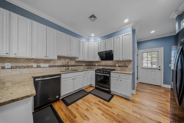 a kitchen with granite countertop white cabinets appliances and wooden floor