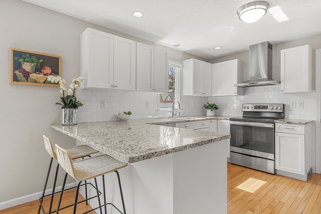 7 Coltsway, Unit 7 Wayland, MA 01778 - Photo 5 of 26 a kitchen with stainless steel appliances granite countertop a stove a sink a microwave a refrigerator and white cabinets with wooden floor
