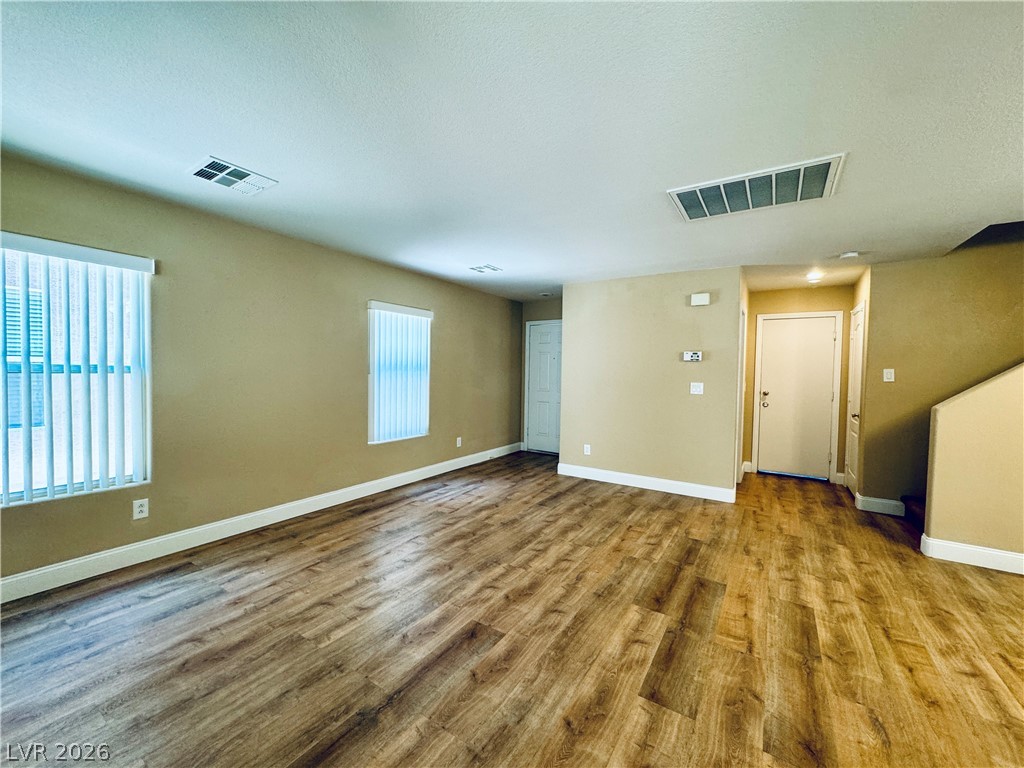 8617 Palomino Ranch Street Las Vegas, NV 89131 - Photo 3 of 27 A versatile living area features durable wood-look flooring and multiple windows, creating a welcoming and adaptable space.
