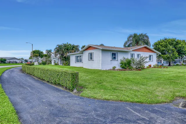 a view of a house with a yard and palm trees