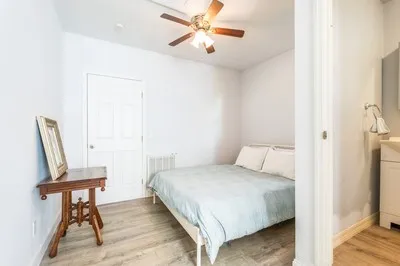 a bedroom with a bed a chair and potted plant on the table