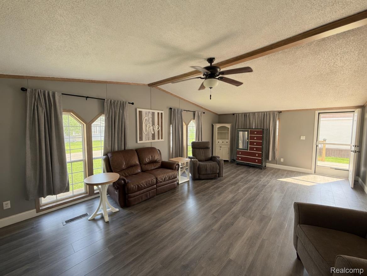 6988 McKean Road Ypsilanti, MI 48197 - Photo 4 of 31 Living room with dark wood-type flooring, ceiling fan, a textured ceiling, and beamed ceiling