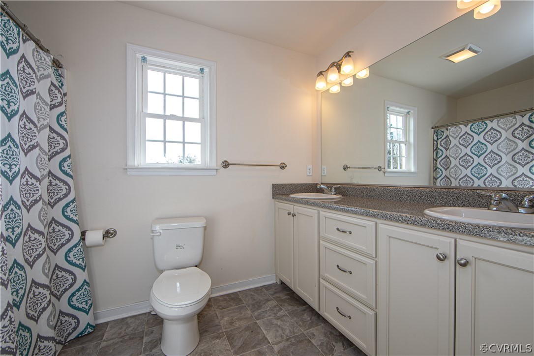 18951 Lundys Road Dinwiddie, VA 23841 - Photo 15 of 27 a bathroom with a granite countertop toilet a sink a large mirror a and a window