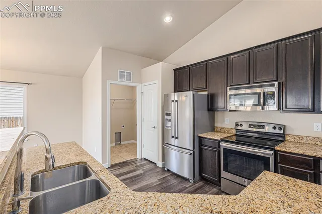 a kitchen with kitchen island granite countertop a stove sink and refrigerator