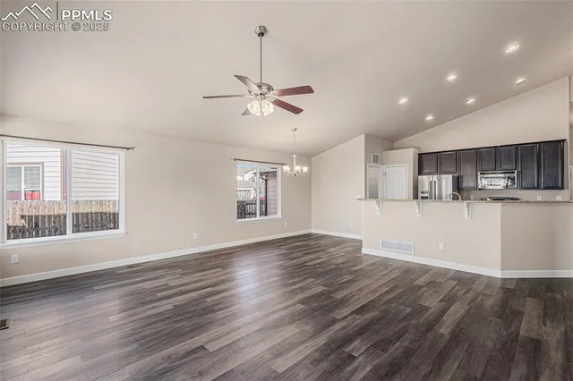 a view of a kitchen with furniture a ceiling fan and wooden floor