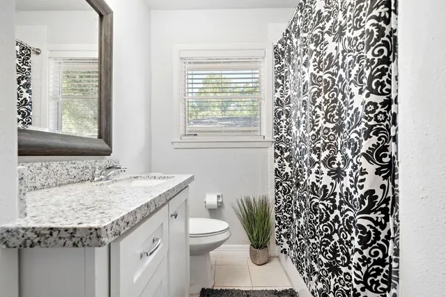 a bathroom with a granite countertop sink and a toilet