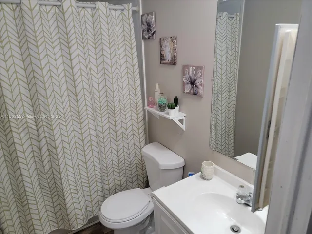 a white toilet sitting next to a white sink and a shower curtain