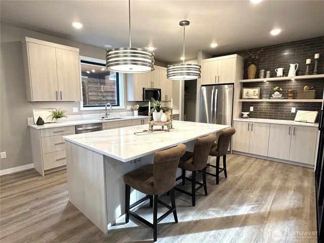a kitchen with stainless steel appliances kitchen island granite countertop a table chairs and a sink