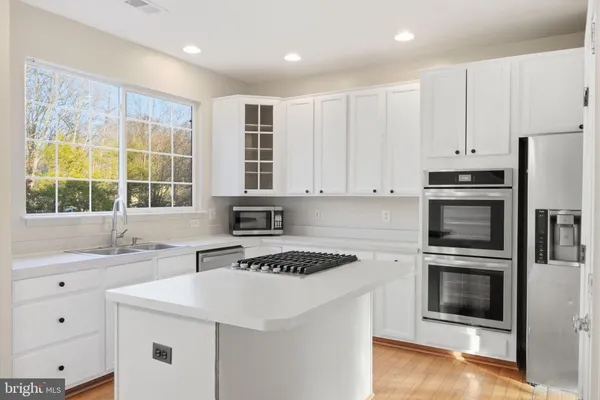 a kitchen with granite countertop a sink stainless steel appliances and window