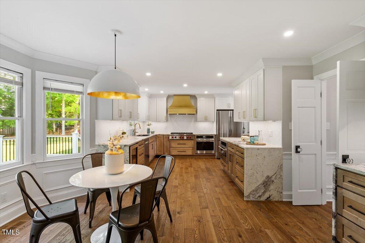 7209 Halstead Lane Raleigh, NC 27613 - Photo 23 of 64 a kitchen with stainless steel appliances kitchen island granite countertop a table chairs and a wooden floor