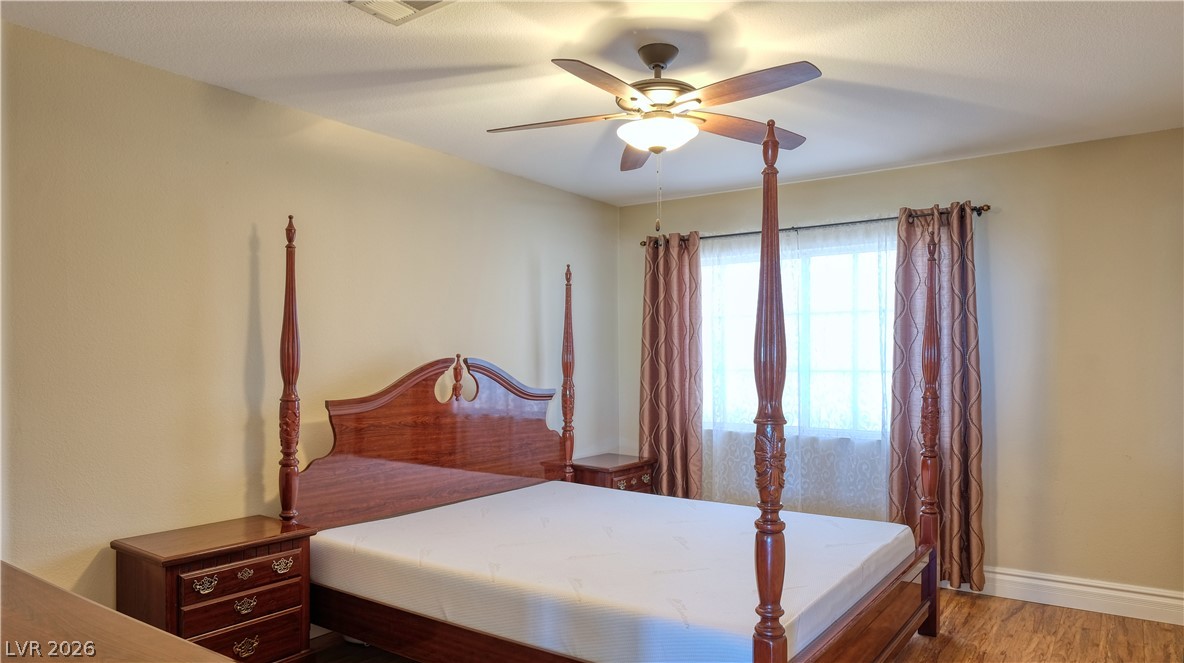 3704 North Campbell Road Las Vegas, NV 89129 - Photo 26 of 38 A comfortable bedroom with rich wood flooring and a classic four-poster bed frame.