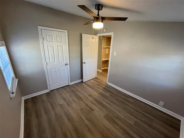 an empty room with wooden floor closet and windows