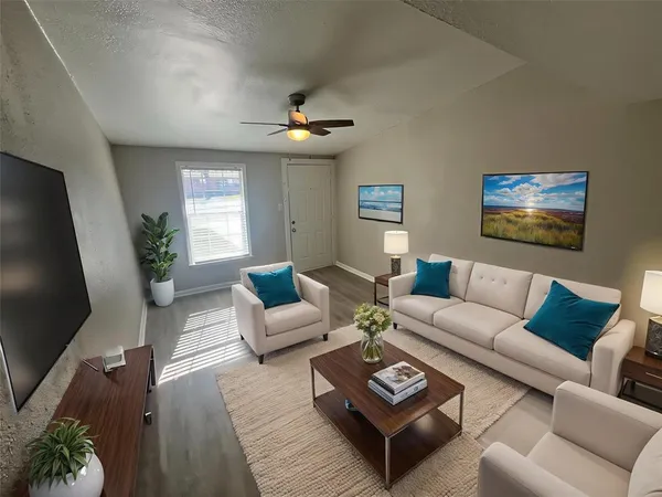 a living room with furniture a ceiling fan and a flat screen tv