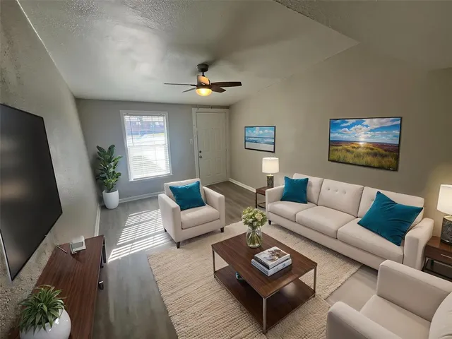 a living room with furniture a ceiling fan and a flat screen tv