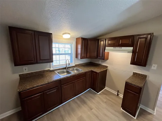 a kitchen with granite countertop wooden cabinets and black appliances