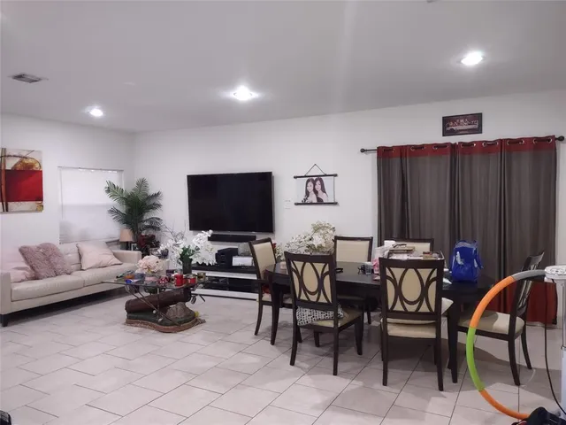 a living room with furniture a flat screen tv and a window