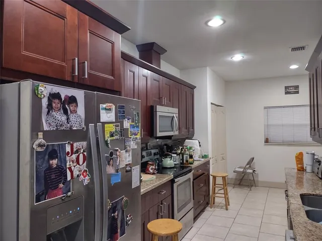 a kitchen with stainless steel appliances granite countertop refrigerator a sink dishwasher a dining table and chairs with wooden floor