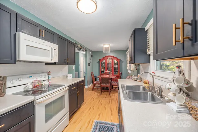 a kitchen with stainless steel appliances a stove top oven a sink a dining table and chairs with wooden floor