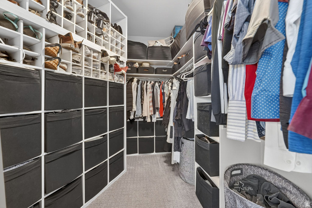 14738 Tangle Hill Road Herriman, UT 84096 - Photo 31 of 66 Walk-in closet featuring built-in shelving, multiple hanging rods, dedicated shoe storage, and soft carpet flooring