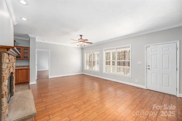a view of an empty room with a window and wooden floor