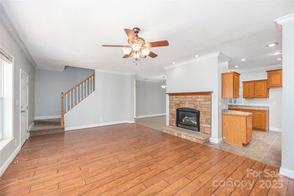 a view of a livingroom with a fireplace a ceiling fan and windows