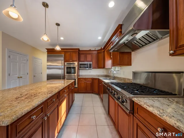 a kitchen with stainless steel appliances granite countertop a stove a sink and a refrigerator