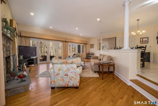 a living room with furniture a flat screen tv and a refrigerator