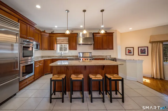 a kitchen with stainless steel appliances kitchen island granite countertop a stove a sink and a refrigerator