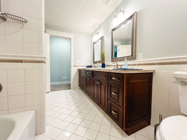 434 Cardon Ridge Drive Smithfield, UT 84335 - Photo 32 of 59 Bathroom with tile walls, wainscoting, double vanity, light tile patterned floors, and shower / tub combination