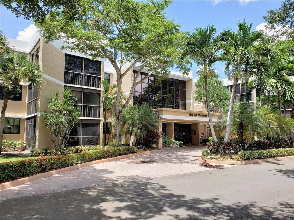 16325 Golf Club Road, Unit 112 Weston, FL 33326 - Photo 3 of 26 a front view of a house with a yard and garage