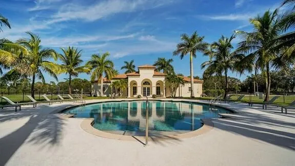 a view of swimming pool with a yard and palm trees