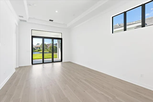 a view of an empty room with window and wooden floor