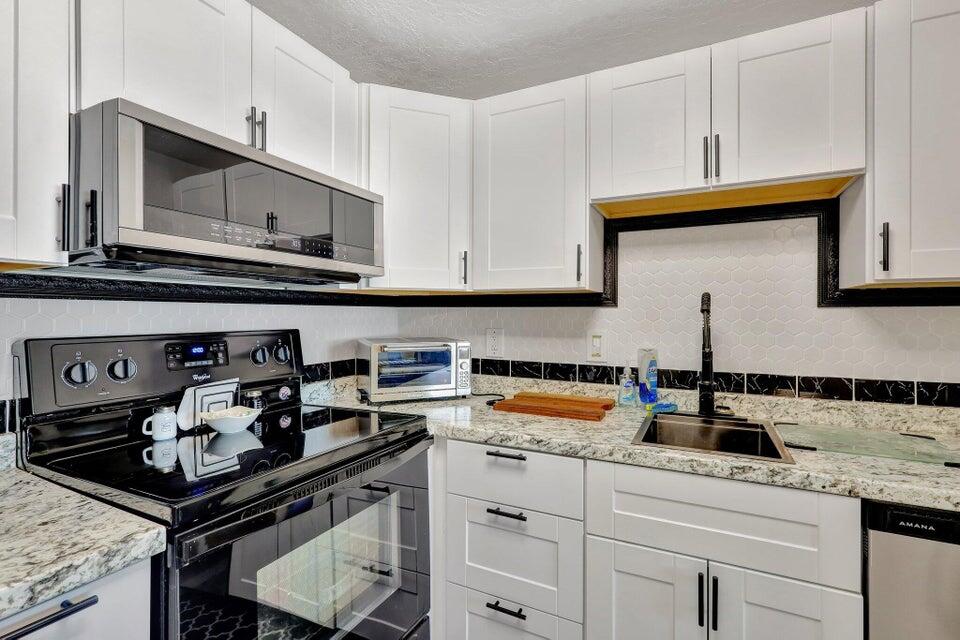 278 Monaco Way, Unit F Delray Beach, FL 33446 - Photo 2 of 19 a kitchen with stainless steel appliances granite countertop a sink stove and cabinets